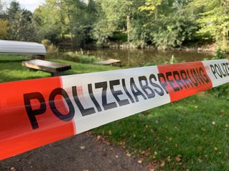 Ein Polizeiabsperrband im Vordergrund, ein Shotterweg mit Gras am Rand, im Hintergrund ein umgedrehtes Ruderboot 